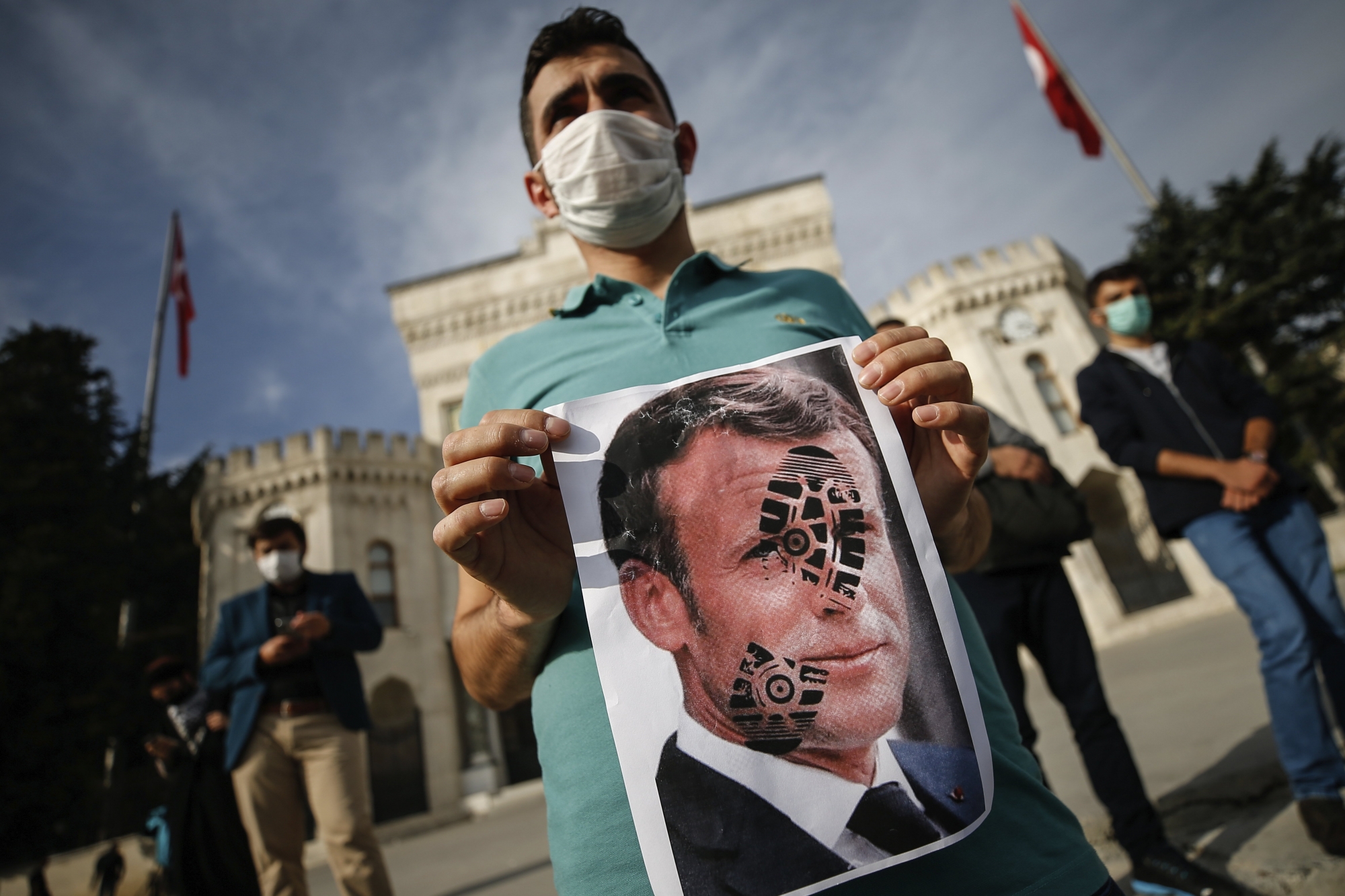Un jeune tient une image du président français macron marqué d'une trace de chaussure en travers de la figure, en signe de soutien au président turc Recep Tayyip Erdogan, qui l'a attaqué avec des mots violents.