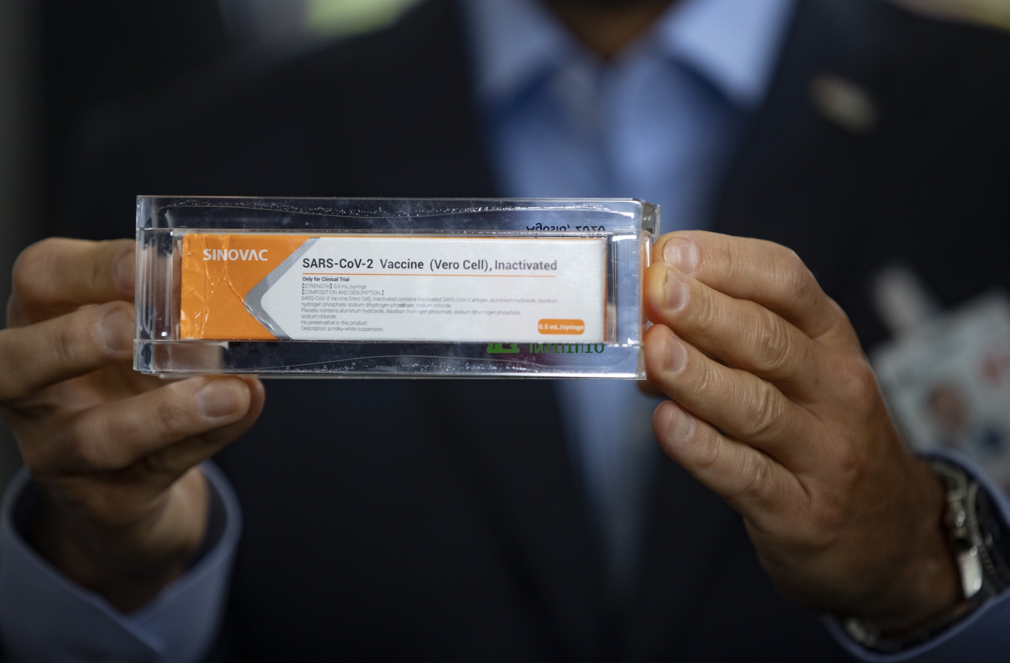 Sao Paulo Governor Joao Doria shows the press a box of an experimental COVID-19 vaccine CoronaVac as containers carrying doses of it are unloaded from a cargo plane that arrived from China at Guarulhos International Airport in Guarulhos, near Sao Paulo, Brazil, Thursday, Nov. 19, 2020. The experimental vaccine is being tested in a partnership with the Butantan Institute and Chinese pharmaceutical company Sinovac. (AP Photo/Andre Penner) La Liberté