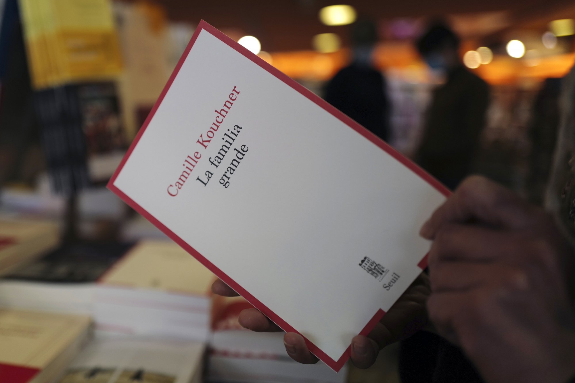 A person holds the book La Familia Grande, by Camille Kouchner, in a bookstore of Paris, Wednesday, Jan. 20, 2021. The book written by prominent French political expert Olivier Duhamel's stepdaughter, Camille Kouchner, accused him of abusing her twin brother during the late 1980s, when the siblings were 13-years-old. The French government pledged on Thursday to toughen laws on the rape of children, as a massive online movement has seen hundreds of victims share accounts about sexual abuses within their families under the hashtag #MeTooInceste. (AP Photo/Francois Mori)