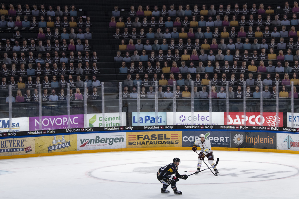 Joueurs en action devant des spectateurs en carton dans la BCF Arena de Fribourg.