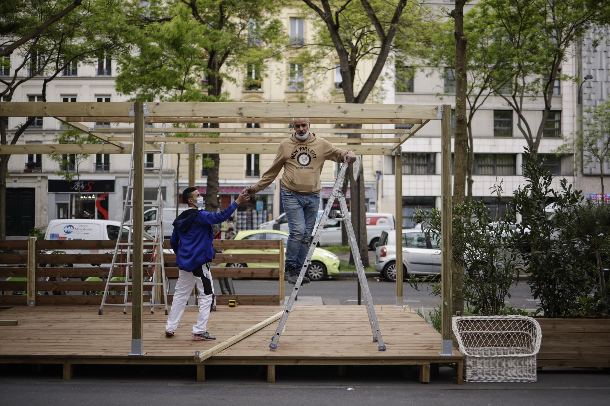 epa09208593 Construction workers build a bar wooden terrace on the eve of its reopening in Paris, France, 18 May 2021. France will ease some of its coronavirus disease (COVID-19) restrictions starting on 19 May, allowing shops, cultural sites, restaurants and cafes admitting customers outdoors, as pressure on hospitals and intensive care units in the country is diminishing. EPA/YOAN VALAT