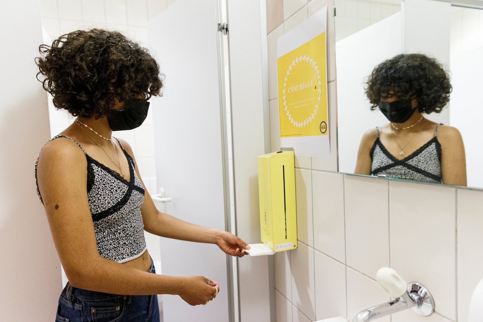 Pauline prend une serviette hygiénique dans le nouveau distributeur installé dans les toilettes du collège des Voiles du Léman, à Préverenges.
