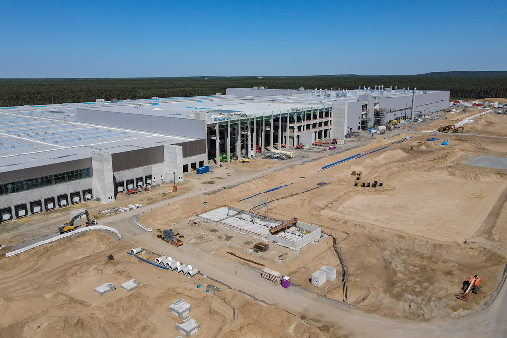 La nouvelle usine Tesla aux portes de Berlin se détache, immense quadrilatère blanc entouré de grues de chantier, sur le paysage fait de forêts sombres et de champs. 