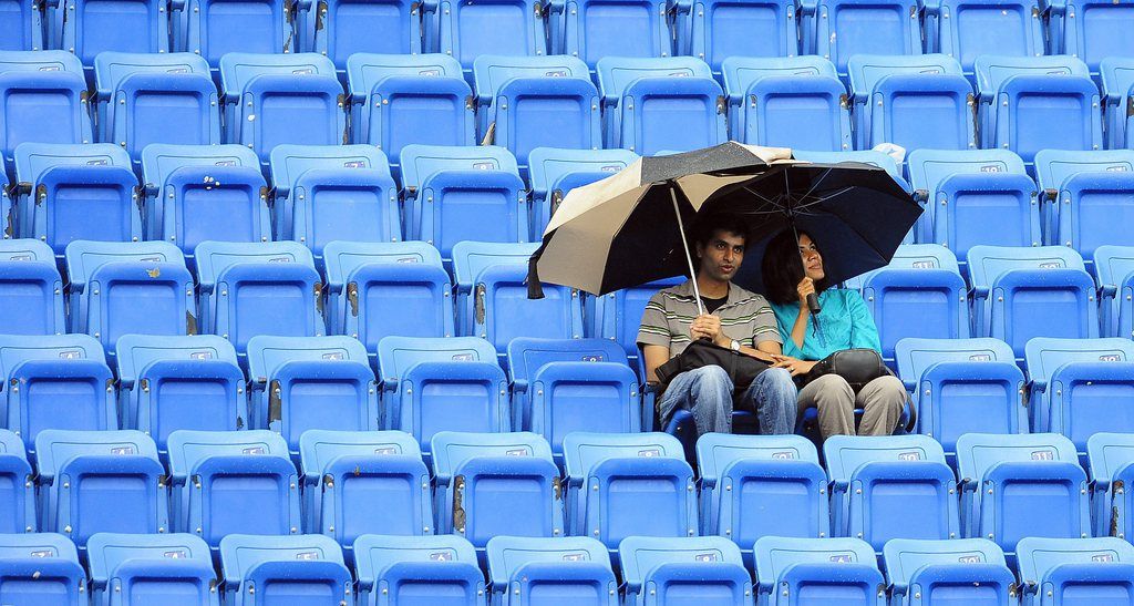 epa02908380 Fans sit under an umbrella in the upper deck as rain falls in Arthur Ashe Stadium shortly before the start of the Seminfinal match between Novak Djokovic of Serbia and Roger Federer of Switzerland on the thirteenth day of the 2011 US Open Tennis Championship at the USTA National Tennis Center in Flushing Meadows, New York, USA 10 September 2011. The US Open has been extended due to weather for the fourth year in a row and the men's final will now be played on 12 September 2011.  EPA/ANDREW GOMBERT