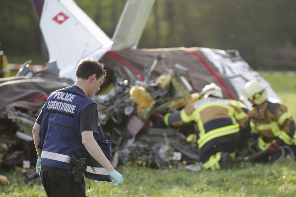 Rescue workers and Police officers work next to the debris of a plane that crashed, in Tatroz near Chatel-St-Denis, Switzerland, Saturday, April 28, 2012. Canton of Fribourg police say a private plane has crashed in a field, claiming five or six lives. (KEYSTONE/Maxime Schmid)