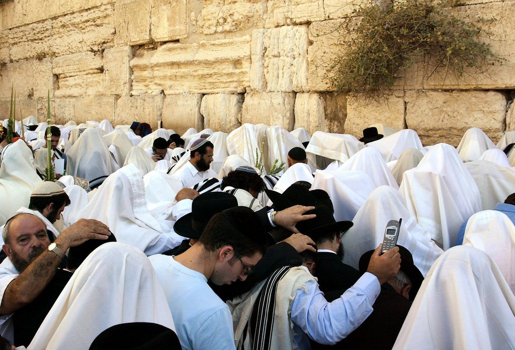 One of the faithful during the Cohenim prayer holds up his mobile phone as the prayer is recited on Monday, 13 October, at the Wailing Wall (behind) in Jerusalem. Tens of thousands of Jews attended the bi-annual prayer held today during the holiday of Succot. The special prayer is recited by Cohens, the ancient high priests in the Biblical Temple who cover their heads with their prayer shawls.  EPA/JIM HOLLANDER