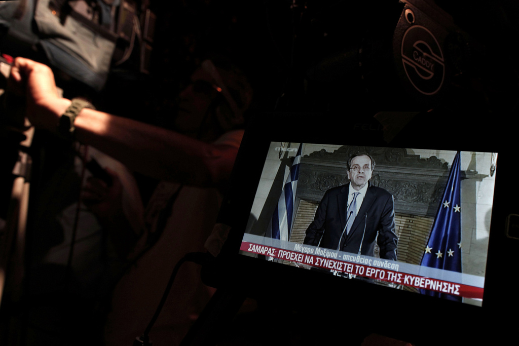 Greek Prime Minister Antonis Samaras is seen in the monitor of a TV crew outside his central Athens office during a live address to the nation early Friday, June 21, 2013. Samaras said he?s determined to avoid early elections despite a deep rift with a coalition ally, which threatened new political instability in the bailed-out country and prompted warnings from international creditors. (AP Photo/Petros Giannakouris)