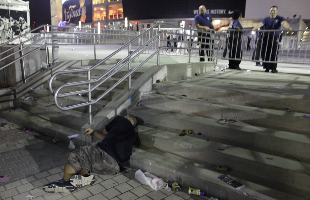 A drunk man sleeps next to security guards  after the Heat won the 2013 NBA Championship against the San Antonio Spurs in Miami Friday, June 21, 2013. The Heat beat the San Antonio Spurs 95-88 in Game 7 of the NBA finals to win their second straight title. (AP Photo/Javier Galeano)