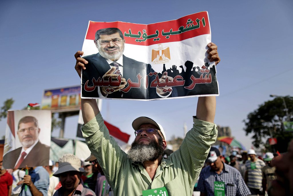 A supporter of Egypt's Islamist President Mohammed Morsi holds a poster with Arabic that reads, "the people support legitimacy for the president," during a rally, in Nasser City, Cairo, Egypt, Wednesday, July 3, 2013. The deadline on the military's ultimatum to President Mohammed Morsi has expired, with 48 hours passing since the time it was issued. Giant cheering crowds of Morsi's opponents have been gathered in Cairo's Tahrir Square and other locations nationwide, waving flags furiously in expection that the military will act to remove the Islamist president after the deadline ends.  (AP Photo/Hassan Ammar)
