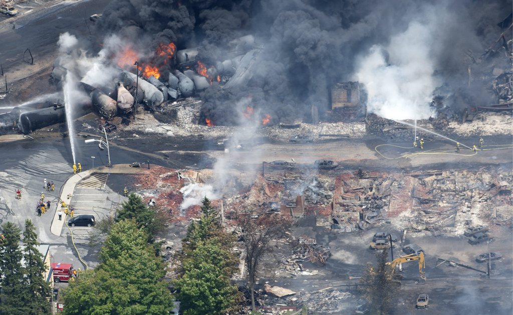 Smoke rises from railway cars that were carrying crude oil after derailing in downtown Lac Megantic, Que., Saturday, July 6, 2013. A large swath of Lac Megantic was destroyed Saturday after a train carrying crude oil derailed, sparking several explosions and forcing the evacuation of up to 1,000 people. (AP Photo/The Canadian Press, Paul Chiasson)