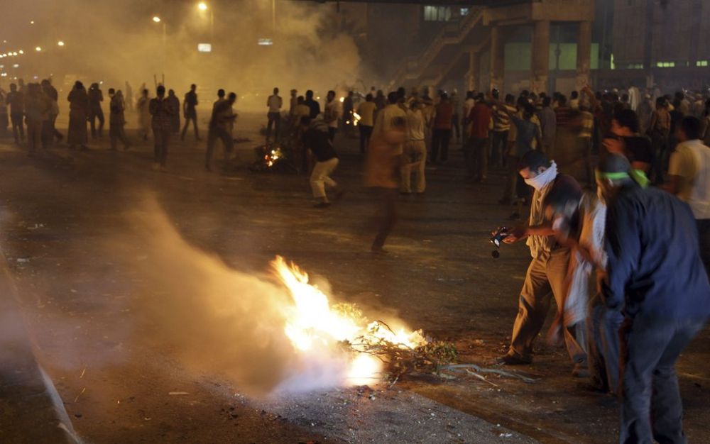 Supporters of Egypt's ousted President Mohammed Morsi block the street with burning tree during clashes with riot police at Nasr City, in Cairo, Egypt, Friday, July 26, 2013. Prosecutors opened an investigation of ousted President Mohammed Morsi on charges including murder and conspiracy with the Palestinian militant group Hamas, fueling tensions amid a showdown in the streets between tens of thousands of backers of the military and supporters calling for the Islamist leader's reinstatement. (AP Photo/Khalil Hamra)