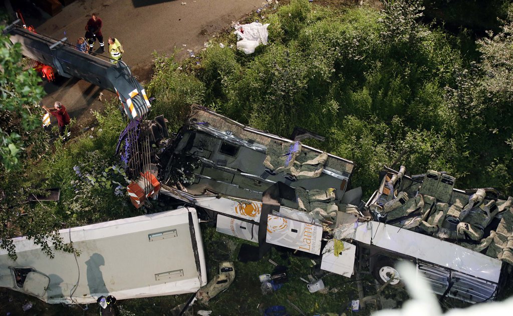 The wreckage of a bus lies on its side following a crash near Avellino, southern Italy, early Monday, July 29, 2013. A tour bus filled with Italians returning home after an excursion plunged off a highway into a ravine in southern Italy on Sunday night after it had smashed into several cars that were slowed by heavy traffic, killing at least 37 people, said police and rescuers. Flashing signs near Avellino, outside Naples, had warned of slowed traffic ahead along a stretch of the A116 autostrada, a major highway crossing southern Italy, before the crash occurred, said highway police and officials, speaking on state radio early Monday. They said the bus driver, for reasons not yet determined, appeared to have lost control of his vehicle. (AP Photo/Gregorio Borgia)