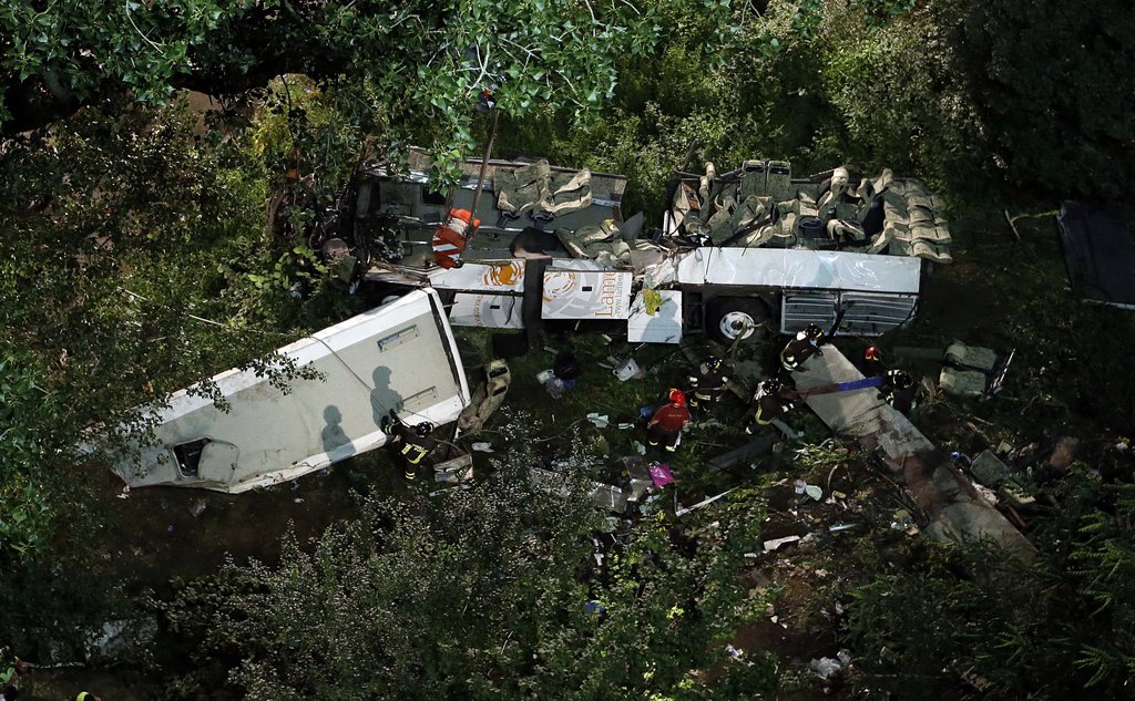 Firefighters work on the wreckage of a bus that plunged off the A16 highway near Avellino, southern Italy, early Monday, July 29, 2013. A tour bus filled with Italians returning home after an excursion plunged off a highway into a ravine in southern Italy on Sunday night after it had smashed into several cars that were slowed by heavy traffic, killing at least 37 people, said police and rescuers. Flashing signs near Avellino, outside Naples, had warned of slowed traffic ahead along a stretch of the A116 autostrada, a major highway crossing southern Italy, before the crash occurred, said highway police and officials, speaking on state radio early Monday. They said the bus driver, for reasons not yet determined, appeared to have lost control of his vehicle. (AP Photo/Gregorio Borgia)