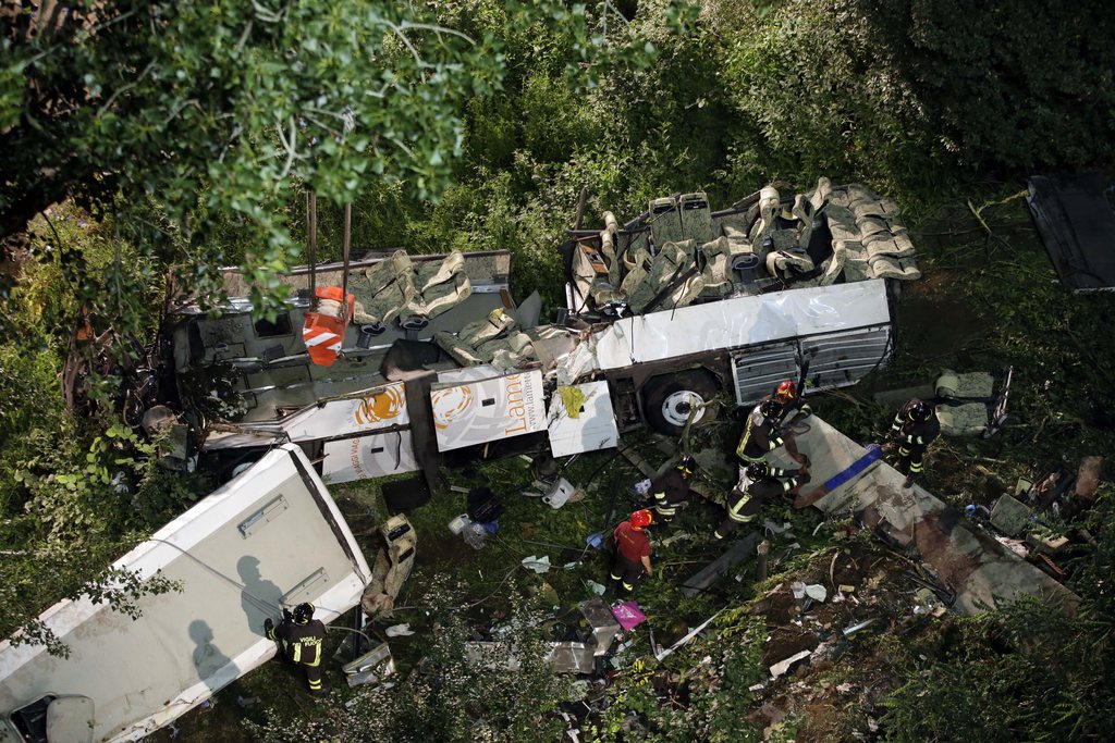 Firefighters work on the wreckage of a bus that plunged off the A16 highway near Avellino, southern Italy, early Monday, July 29, 2013. A tour bus filled with Italians returning home after an excursion plunged off a highway into a ravine in southern Italy on Sunday night after it had smashed into several cars that were slowed by heavy traffic, killing at least 37 people, said police and rescuers. Flashing signs near Avellino, outside Naples, had warned of slowed traffic ahead along a stretch of the A116 autostrada, a major highway crossing southern Italy, before the crash occurred, said highway police and officials, speaking on state radio early Monday. They said the bus driver, for reasons not yet determined, appeared to have lost control of his vehicle. (AP Photo/Gregorio Borgia)