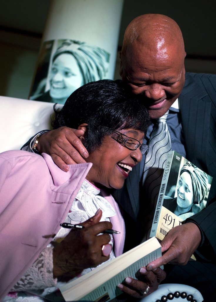 Winnie Madikizela-Mandela, left, reacts with Justice Minister Jeff Radebe, right, during her book launch at the Constitution Hill in Johannesburg, South Africa, Thursday, Aug. 8, 2013. Mandela, an Apartheid-era struggle stalwart, was joined by family and friends at a former women's prison in Johannesburg's Constitutional Hill to launch "491 days" - an account of her arrest and imprisonment in solitary confinement. (AP Photo/Themba Hadebe)