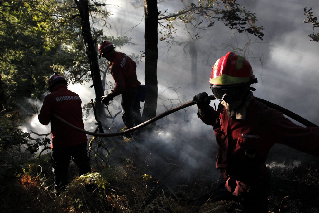Portuguese firefighters work to extinguish a fire in Adsamo, near Vouzela, Portugal, Friday, Aug. 23, 2013. More than 600 Portuguese firefighters were battling six new wildfires a day after one firefighter was killed and nine others injured when gusting winds caused a fire to change direction. Portugal's National Civil Protection agency said water-bombing planes were also being used to fight fires Friday in north-central Portugal. (AP Photo/Francisco Seco)