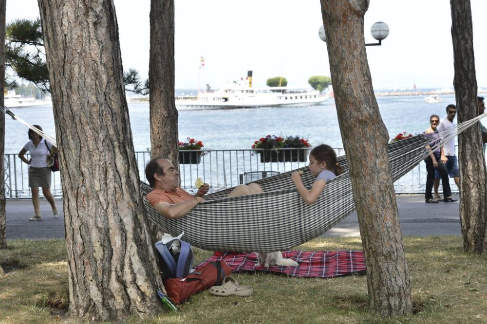 Julio et Luisa installer dans un hamac dans le Jardin Anglais dejeune tranquillement, ce dimanche 14 juillet 2013 a Geneve. (KEYSTONE/Martial Trezzini)