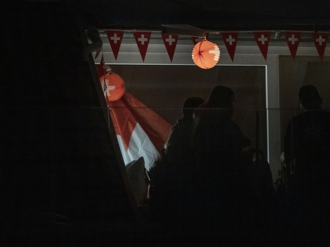 Un lampion, une chaîne de fanions et un drapeau suisse photographiés le 30 juillet 2022 sur un balcon à Zurich attendent le premier août pour fêter la Suisse.