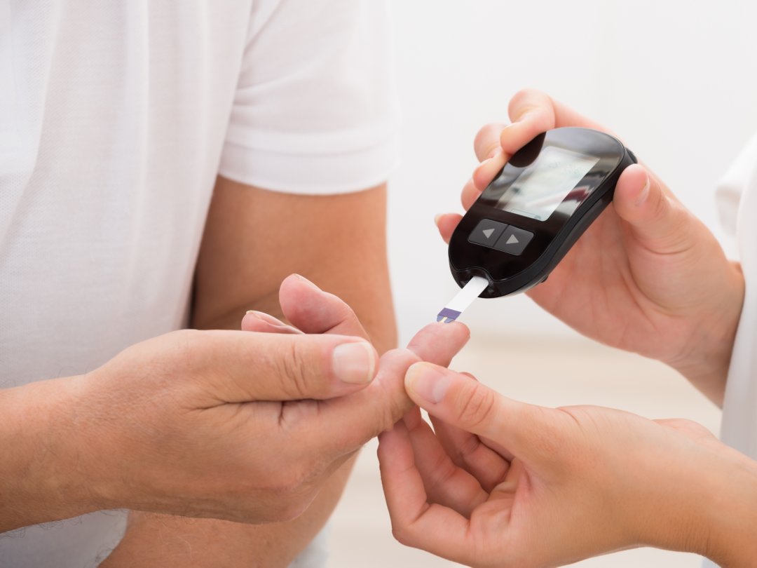 Close-up Of Doctor's Hand Using Glucometer On Patient's Finger