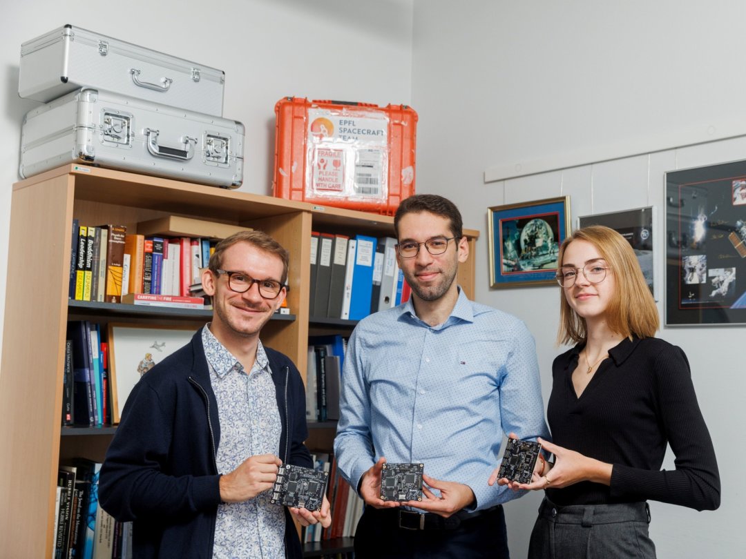 Robin Bonny, Aziz Belkhiria et Alix Schmutz, membres de l'EPFL Spacecraft Team, présentent des répliques de l'ordinateur de bord qui sera envoyé dans l'espace, en janvier prochain.