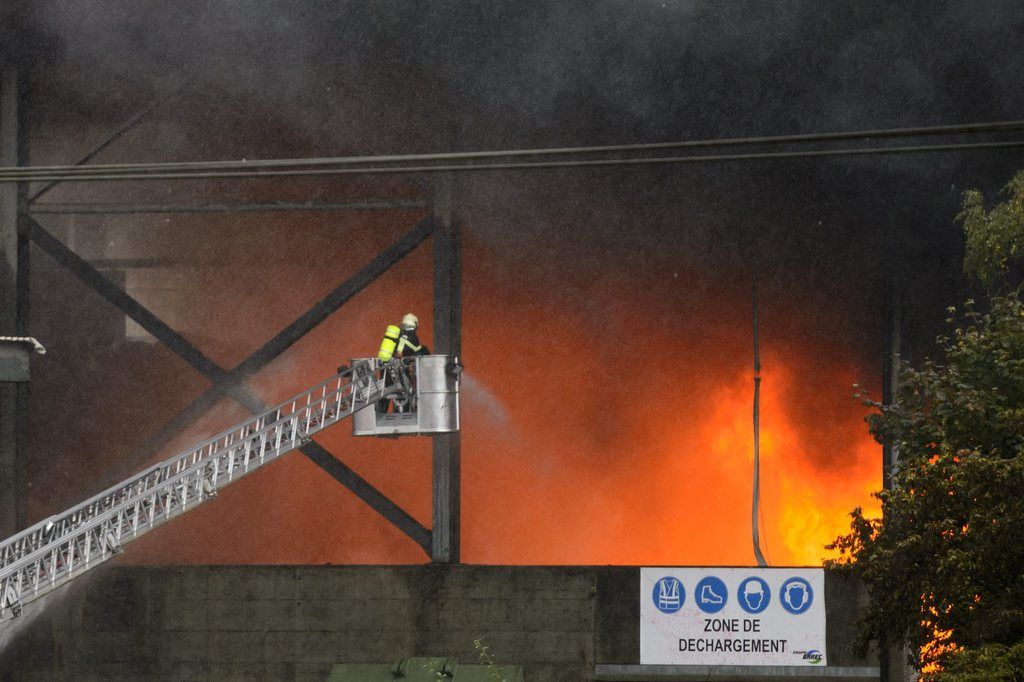 Des pompiers essayent d'eteindre les flammes d'un feu d'entrepôt de carcasses de voitures.