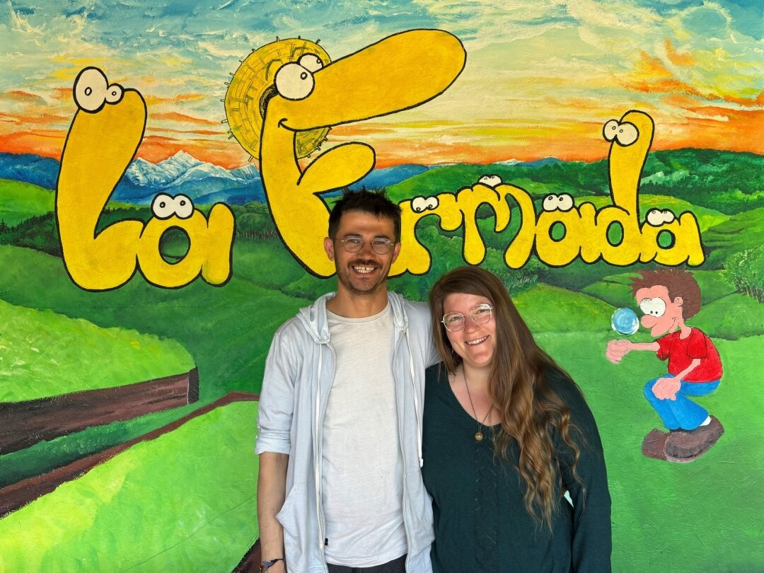 «Nous nous sommes installés à Saubraz pour réaliser notre rêve de vie simple et proche de la nature», expliquent Danaé Isely et Ali Mehrzad. Ils posent devant une fresque, en cours de réalisation, signée Yoann Badel, leur voisin.