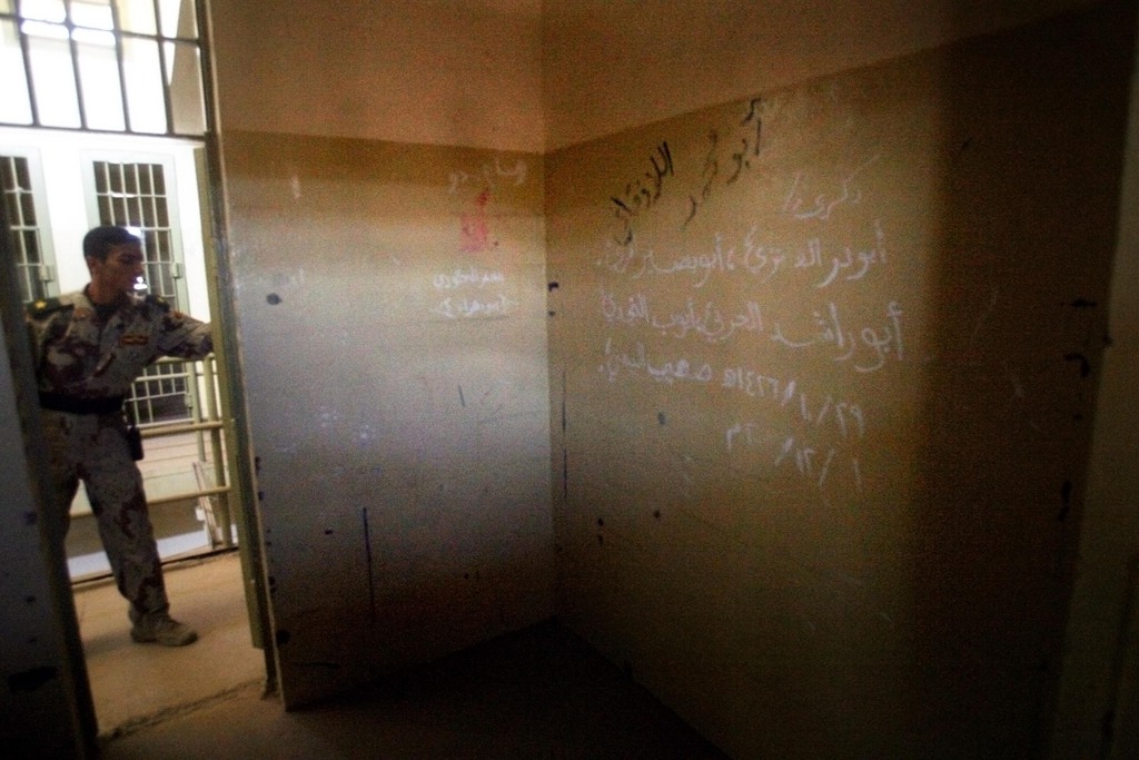 FILE - in this Sept. 2, 2006 file photo, an Iraqi army soldier closes the door of a cell with the names of suspected foreign insurgents from Syria, Saudi Arabia and Yemen written on the wall, in Abu Ghraib prison on the outskirts of Baghdad, Iraq. Al-Qaida's branch in Iraq claimed responsibility Tuesday for audacious raids on two high-security prisons on the outskirts of Baghdad this week that killed dozens and set free hundreds of inmates, including some of its followers. (AP Photo/Khalid Mohammed, File)