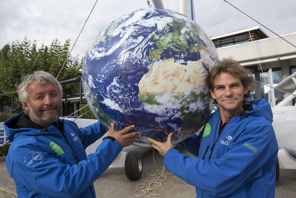 Le navigateur suisse Yvan Bourgnon (gauche), et le navigateur français Vincent Beauvarlet, droite, posent avec une mappemonde devant leur catamaran avant leur défi de tour du monde à la voile.