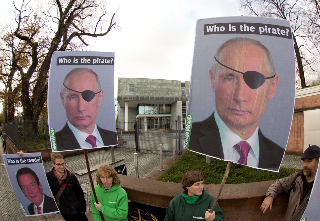 epa03937948 Activists of the environmental organization Robin Wood hold placards depicting Russia's President Vladimir Putin and former German Chancellor Gerhard Schroeder (L) as they demonstrate in front of the International Tribunal for the Law of the Sea in Hamburg, Germany, 06 November 2013. An international tribunal was holding a hearing into the dispute between the Netherlands and Russia over the seizure by Russian forces of a Dutch-flagged Greenpeace vessel 'Arctic Sunrise' after activists had attempted to storm an oil rig in the remote Pechora Sea in September.  EPA/CHRISTIAN CHARISIUS