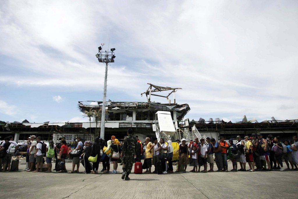 epa03947688 Passengers wait for a rescue airplane at a damaged aiport in the super typhoon devastated city of Tacloban, Leyte province, Philippines, 13 November 2013. Aid workers and relief supplies were being poured into eastern provinces hit by Typhoon Haiyan, which aid agencies and officials estimated has left thousands dead and staggering destruction in its wake. The official death toll in the Philippines from one of the world?s strongest typhoons rose to 1,833, the national disaster relief agency said with many towns still unaccounted for.  EPA/RITCHIE B. TONGO