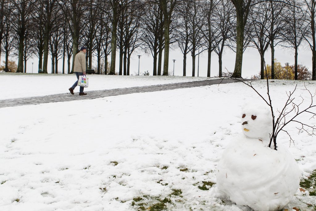 Un homme traverse le Parc de Valency ou un bonhomme de neige etait cree, ce jeudi 21 novembre 2013 a Lausanne. (KEYSTONE/Aline Staub)