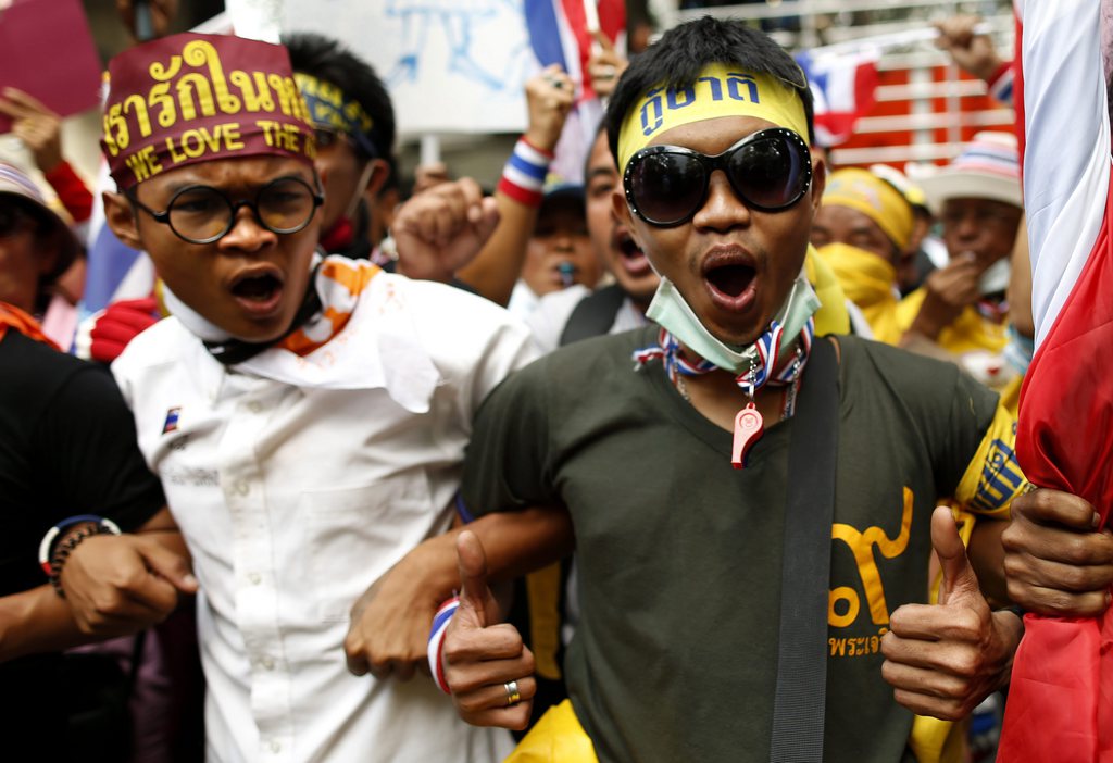 epa03994780 Thai anti-government protesters shout slogans against policemen during a massive rally at the Royal Thai Police headquarters in Bangkok, Thailand, 18 December 2013. A mass of anti-government protests forced Prime Minister Yingluck Shinawatra to dissolve the parliament on 09 December 2013 and call for a snap election on 02 February 2014, and seeking to set up a People's Council with 400 appointed members to push through political reforms ahead of the next polls.  EPA/RUNGROJ YONGRIT