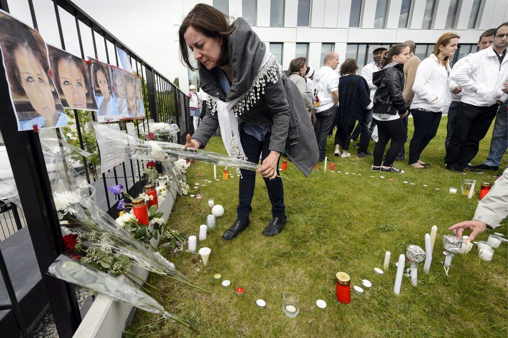Une femme dépose une fleur sous un portrait de Marie devant le Tribunal des mesures de contrainte de l'office du juge d'application des peines du canton de Vaud lors d'une marche blanche Tribunal des mesures de contrainte de l'office du juge d'application des peines le lundi 20 mai 2013 a Lausanne.