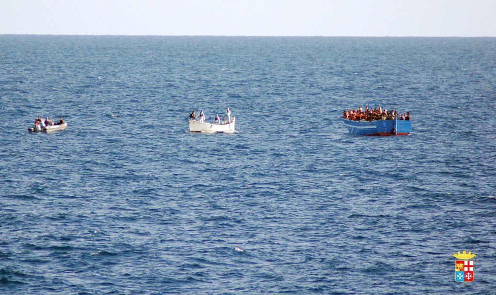 epa04036945 A handout photograph provided by the Italian Navy shows a boat with 200 migrants (R), off the coast of Lampedusa, Italy, 22 January 2014. The Italian navy said on 22 January it has sent a frigate and helicopter to rescue some 200 migrants onboard a boat in the central Mediterranean. The vessel was seen around 90 nautical miles (170 kilometres) south of the island of Lampedusa, Italy's southern outpost which is roughly halfway between Sicily and Tunisia.  EPA/ITALIAN NAVY / HANDOUT  HANDOUT EDITORIAL USE ONLY/NO SALES