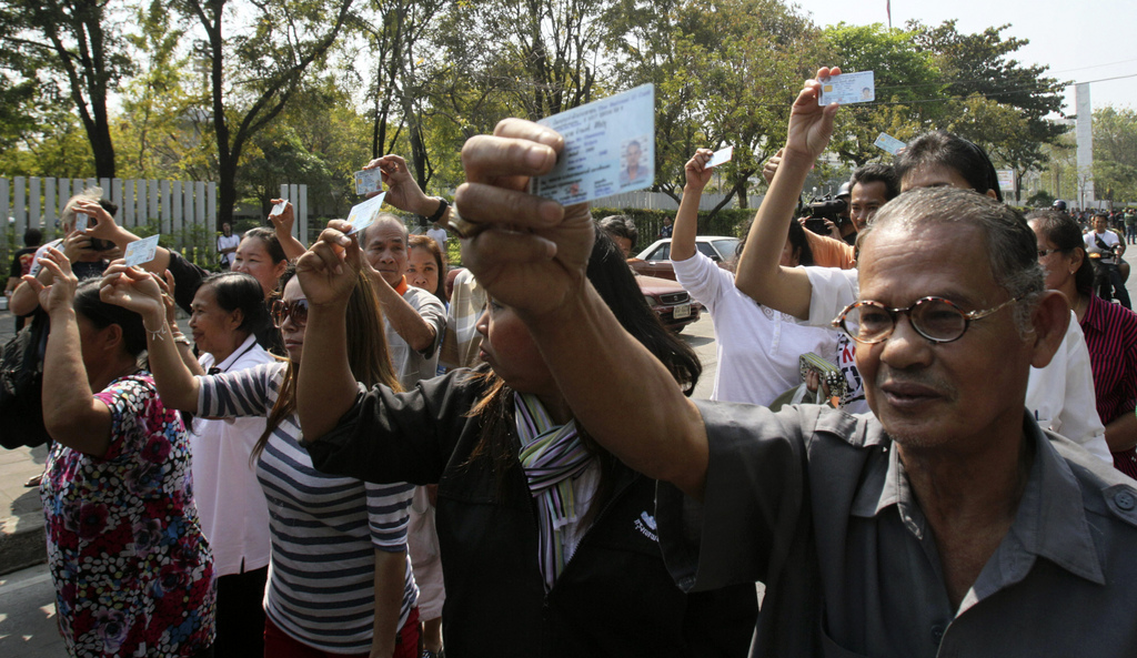 Pro-election supporters hold up their ID cards to demand to vote outside Din Daeng polling station in Bangkok Sunday, Feb. 2, 2014. Thailand's tense national election got underway Sunday with protesters forcing the closure of hundreds of polling stations in the capital amid fears of more bloodshed a day after gun battles in Bangkok left seven people wounded. (AP Photo/Sakchai Lalit)