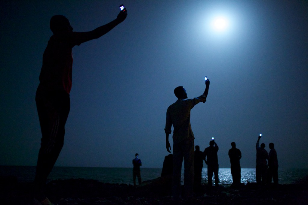 In this photo provided on Friday Feb. 14, 2014 by World Press Photo, the World Press Photo of the Year 2013 by John Stanmeyer, USA, VII for National Geographic, shows African migrants on the shore of Djibouti city at night, raising their phones in an attempt to capture an inexpensive signal from neighboring Somalia in Djibouti City, Djibouti, Feb. 26, 2013. (John Stanmeyer/VII for National Geographic) 
NO SALES, THIS MATERIAL IS FOR SINGLE USE PUBLICATIONS IN PRINT OR FOR A TEMPORARY ONLINE PUBLICATION, AND MAY BE USED EXCLUSIVELY TO PUBLICIZE THE 2014 WORLD PRESS CONTEST AND EXHIBITION. IT MAY NOT BE PUBLISHED AS PART OF AN ARTICLE OR ANY OTHER ITEM THAT CONTAINS NO DIRECT LINK TO WORLD PRESS PHOTO AND ITS ACTIVITIES. THE PICTURE MAY NOT BE CROPPED OR MANIPULATED IN ANY WAY. KEYSTONE PROVIDES ACCESS TO THIS PUBLICLY DISTRIBUTED HANDOUT PHOTO. THE COPYRIGHT IS OWNED BY A THIRD PARTY **  This material is for single publications in print or for a temporary online publication, and may be used exclusively to publicize the 2014 World Press Photo contest and exhibition. It may not be published as part of an article or any other item that contains no direct link to World Press Photo and its activities without prior permission from the photographer or agency.