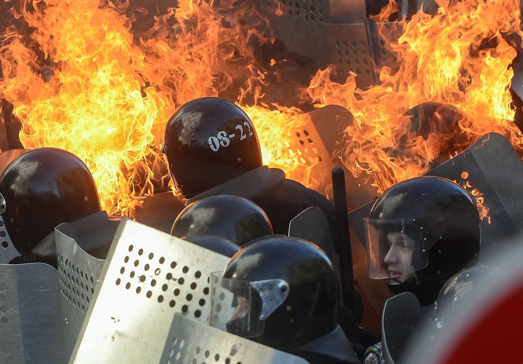 epa04086350 Riot policemen in flames clash with protesters during the continuing protest in downtown Kiev, Ukraine, 18 February 2014. A least three protesters were killed in clashes with police on 18 February, Ukrainian opposition activists say. Violence erupted in the Ukrainian capital after anti-government protesters broke through a police cordon in front of parliament. Protester marched toward the parliament to demand constitutional reforms that would curb the powers of President Viktor Yanukovych. Ukraine has been mired in political crisis since November after the government backed away from a trade agreement with the European Union and signed a 15-billion-dollar loan deal with Russia instead.  EPA/ANDREW KRAVCHENKO