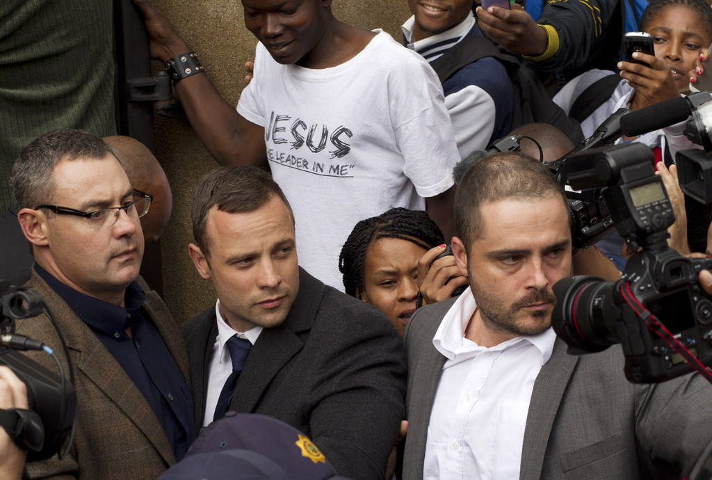 Oscar Pistorius, center, is escorted out by police officers as he leaves  the high court on the second day of his trial in Pretoria, South Africa, Monday, March 3, 2014. Oscar Pistorius is charged with murder for the shooting death of his girlfriend, Reeva Steenkamp, on Valentines Day in 2013. (AP Photo/Themba Hadebe)