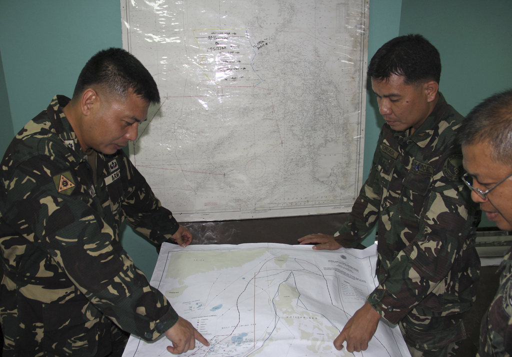 In this photo released by the Armed Forces of the Philippines, Western Command PIO, Filipino government troopers look at a map as they continue the search for the missing plane of Malaysian Airlines at Antonio Bautista Air Base in Puerto Princesa City, Palawan province after conducting air search for the missing plane of Malaysian Airlines on Saturday March 8, 2014. Search and rescue crews across Southeast Asia scrambled to find a Malaysia Airlines Boeing 777 that disappeared from air traffic control screens over waters between Malaysia and Vietnam early Saturday with 239 people aboard. (AP Photo/Armed Forces of the Philippines, Western Command PIO)