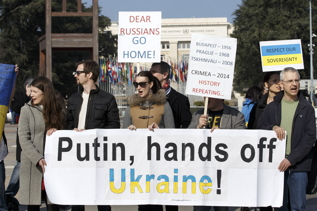 Pro Ukrainian protesters hold a banner reading "Putin hands off Ukraine" and posters "Dear Russinas go home" and "Respect our sovereignty" during a rally against the Russian military's actions in Crimea on the Place des Nations in front of the European headquarters of the United Nations, in Geneva, Switzerland, Saturday, March 8, 2014. (KEYSTONE/Salvatore Di Nolfi)