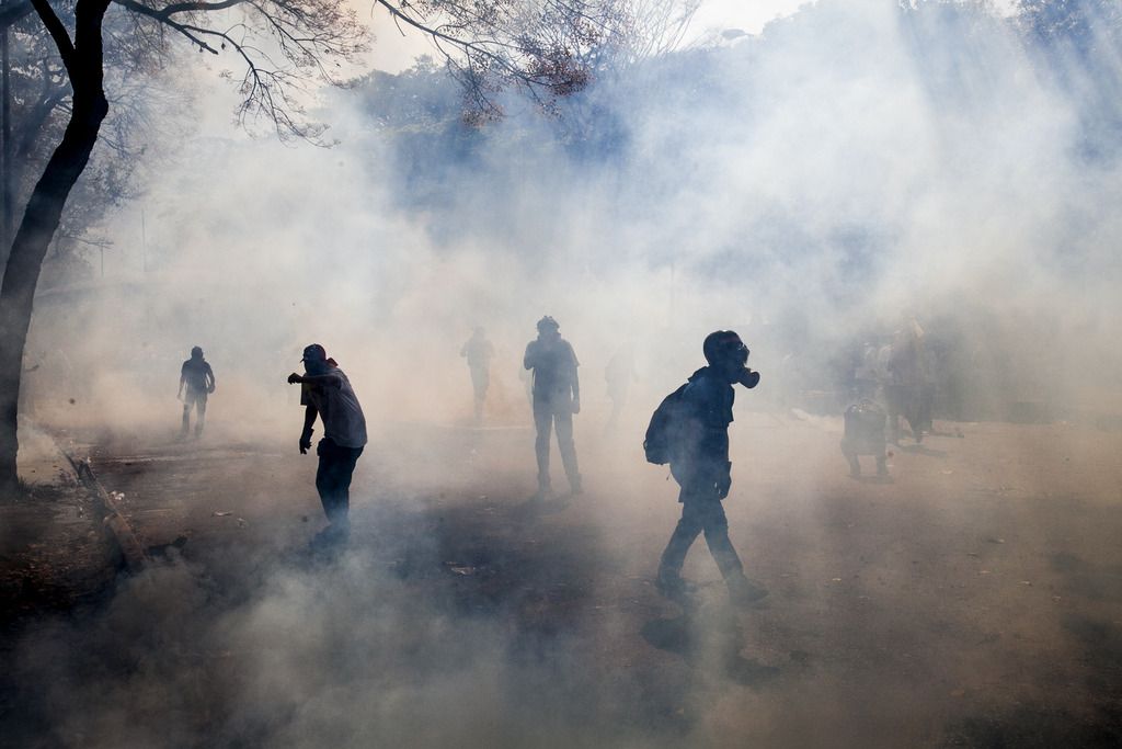 Des manifestants marchent dans des nuages de gaz lacrymogène dans les rues de Caracas.