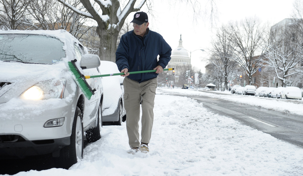 Gary Staples, of Washington, clears of snow off of his car near Capitol Hill in Washington, Monday, March 17, 2014. Snow has been falling in parts of the Mid-Atlantic and Northeast as winter-weary motorists faced another potentially treacherous commute Monday morning, just days before the start of spring. (AP Photo/Susan Walsh)