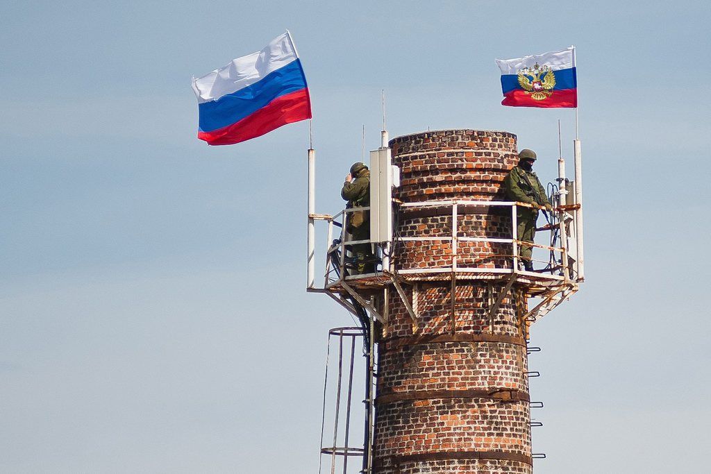 Hommes armés et drapeaux russes flottent sur une cheminée, en Crimée.
