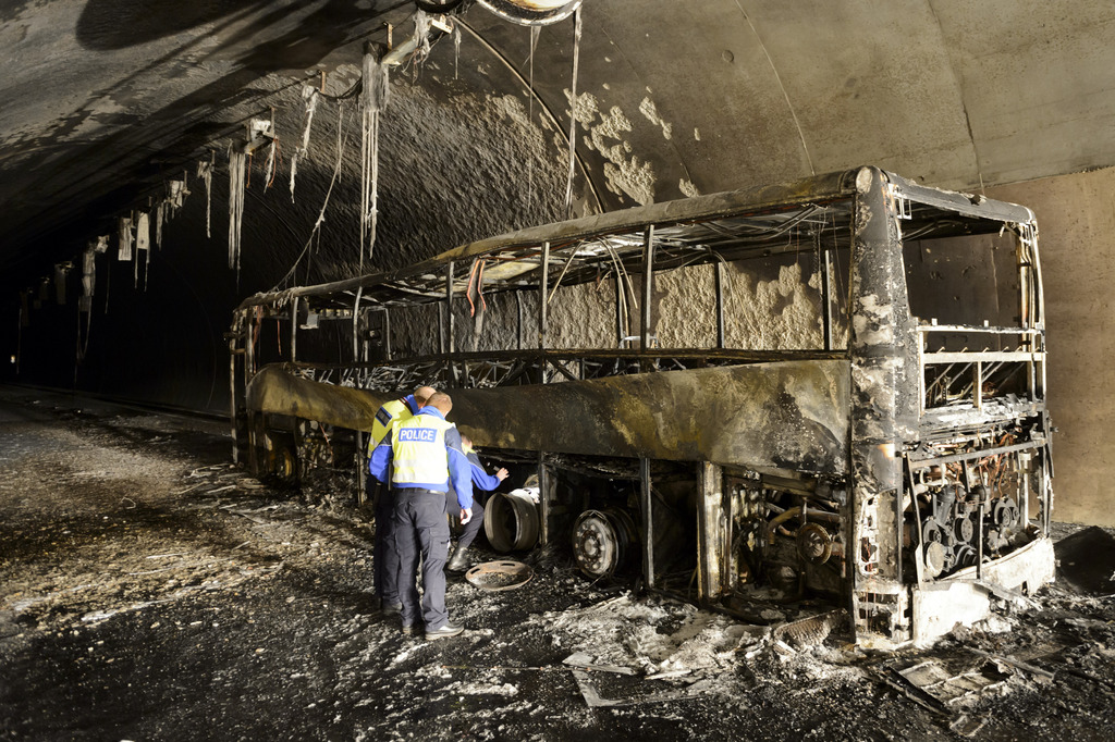 Des policiers vaudois observent la carcasse d'un car qui a brule dans le tunnel Arrissoules sur l'autoroute A1 entre Yverdon et Estavayer ce jeudi 20 mars 2014 a Yvonand. Un car a pris feu jeudi matin sur l'A1 dans le tunnel d'Arrissoules, pres d'Yvonand (VD). L'autoroute est actuellement ferm?e dans les deux sens.(KEYSTONE/Laurent Gillieron)