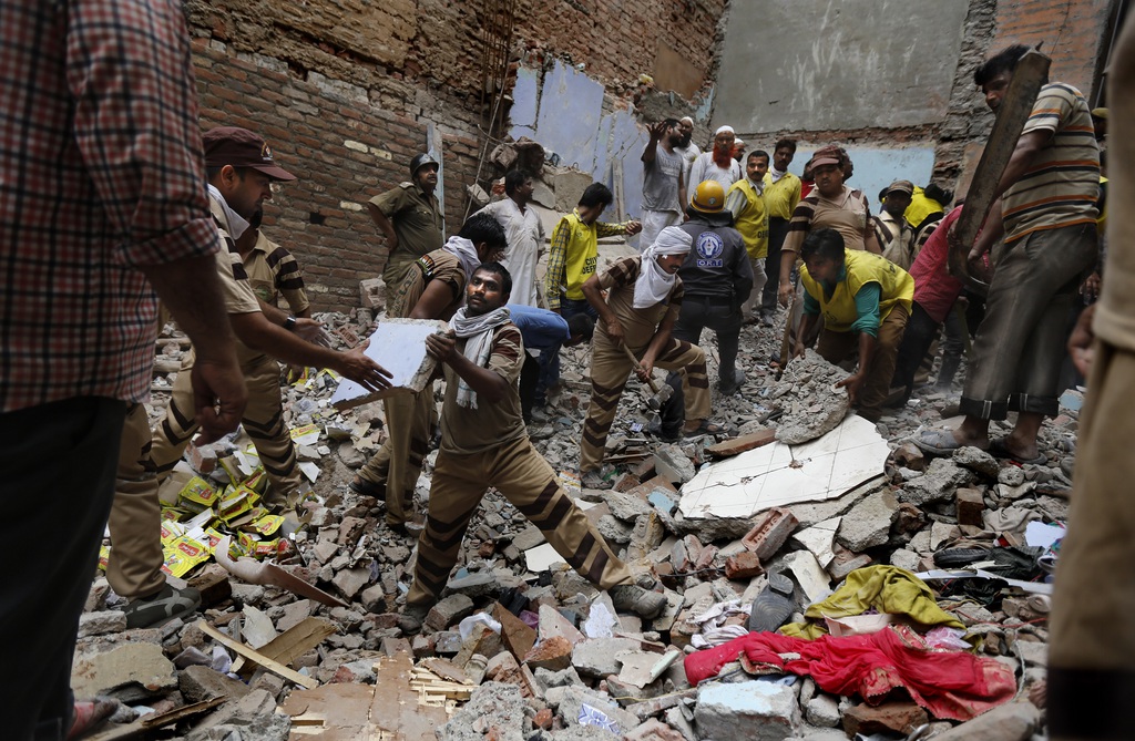 Rescue workers clear debris at the site of a building collapse in New Delhi, India, Saturday, June 28, 2014. A dilapidated building collapsed in the Indian capital on Saturday, killing at least seven people as rescuers searched for others believed to be trapped. (AP Photo/Altaf Qadri)