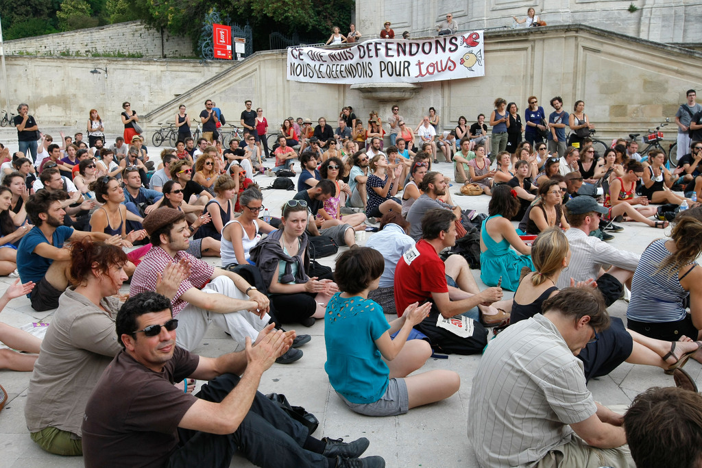 Part-time and temporary arts workers, striking artists and theater personnel, known as 'intermittents', applaud, during a general assembly, in Avignon, France,  Friday, July 4, 2014. Organizers of one of Europe?s premier theater festivals are cancelling some shows amid a protest movement by cultural workers over changes to their off-season unemployment benefits. The director of the Festival d?Avignon, Olivier Py, told journalists in Avignon that two plays scheduled for Friday?s opening night have been called off. The CGT union announced a strike, but it?s unclear how many workers will take part. Banner reads :"That we defend, we defend for all". (AP Photo/Claude Paris)