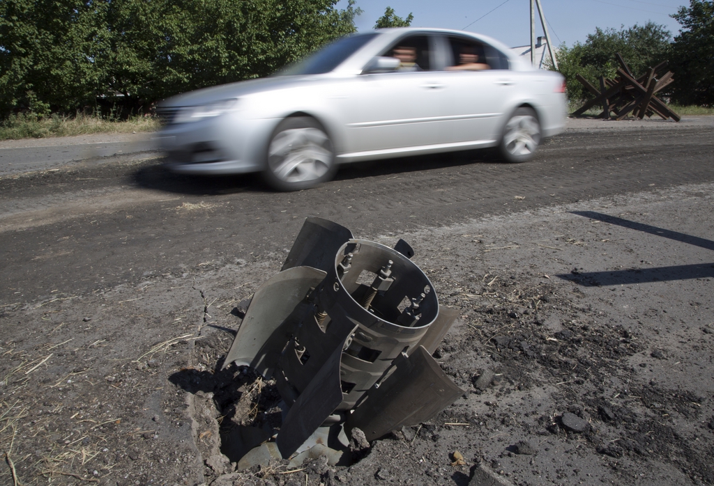 A car drives past a tail of a missile in the city of Lisichansk, Luhansk region, eastern Ukraine Saturday, July 26, 2014. Volunteers from the Donbas Battalion, a volunteer militia for a united Ukraine, told The Associated Press their units, along with the Ukrainian army, regained control of Lisichansk on Friday. (AP Photo/Dmitry Lovetsky)