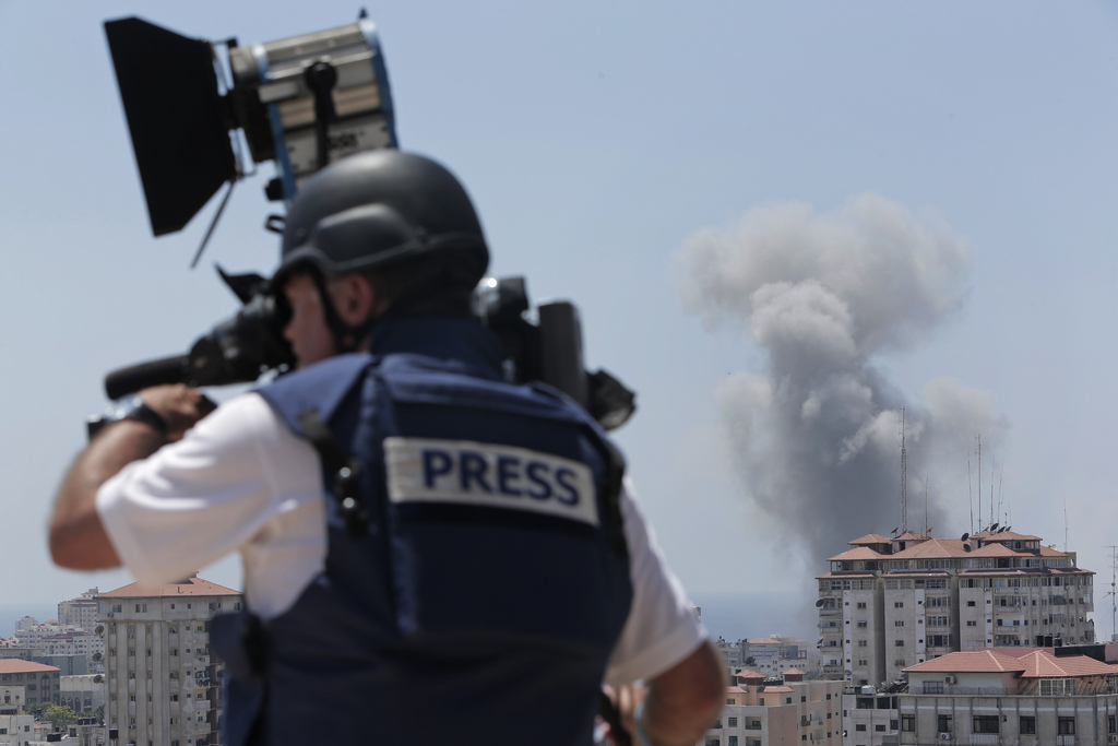 A news cameraman films at a live position as in the background smoke rises from an Israeli strike in Gaza City, Sunday, July 27, 2014. Hamas on Sunday agreed to observe a 24-hour humanitarian truce ahead of a major Muslim holiday after initially rejecting such an offer by Israel, as the two sides wrangled over setting the terms of a lull the international community hopes can be expanded into a more sustainable truce. (AP Photo/Lefteris Pitarakis)