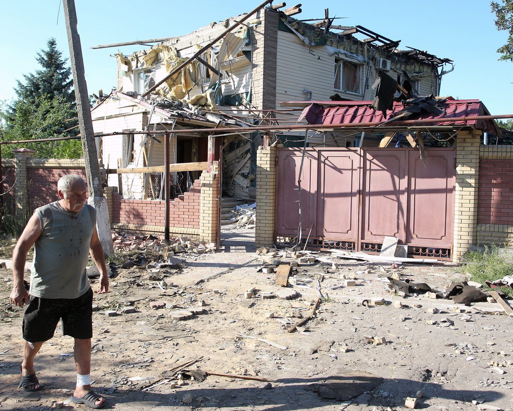 epa04333221 A man walks past a damaged house in Horlivka, Ukraine, 27 July 2014. According to reports, Ukrainian army has taken measures to regain control over Horlivka, a town considered a separatist stronghold.  EPA/IGOR KOVALENKO