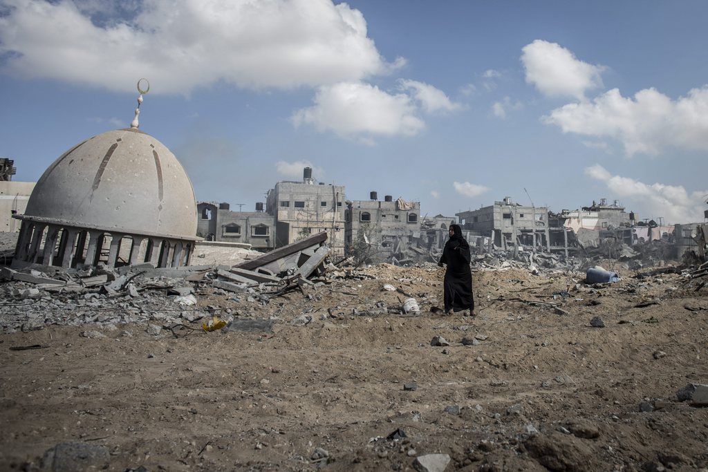epa04339639 A Palestinian woman walks between destroyed houses and Israeli tank tracks in Khuzaa, central Gaza Strip, 03 August 2014. Israeli ground troops withdrew from the Gaza Strip, but airstrikes continued, killing at least 15 Palestinians. The Palestinian death toll has risen to at least 1,737 since 08 July, including about 400 children, the Gaza Health Ministry said. Sixty-three Israeli soldiers, two Israeli civilians and a Thai national have also been killed. Rights groups have estimated that more than 10,000 houses were destroyed or badly damaged by Israel.  EPA/OLIVER WEIKEN